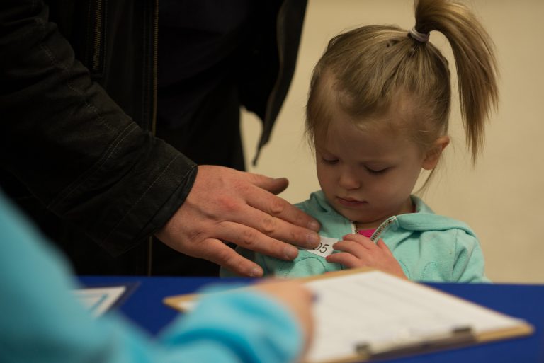 little blond girl putting on a name tag